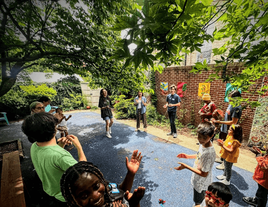 Children and teaching artists clapping and moving together outdoors during Movement Studio