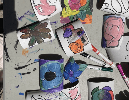 Painted paper cups and markers on a table from a BuildaBridge art-making session
